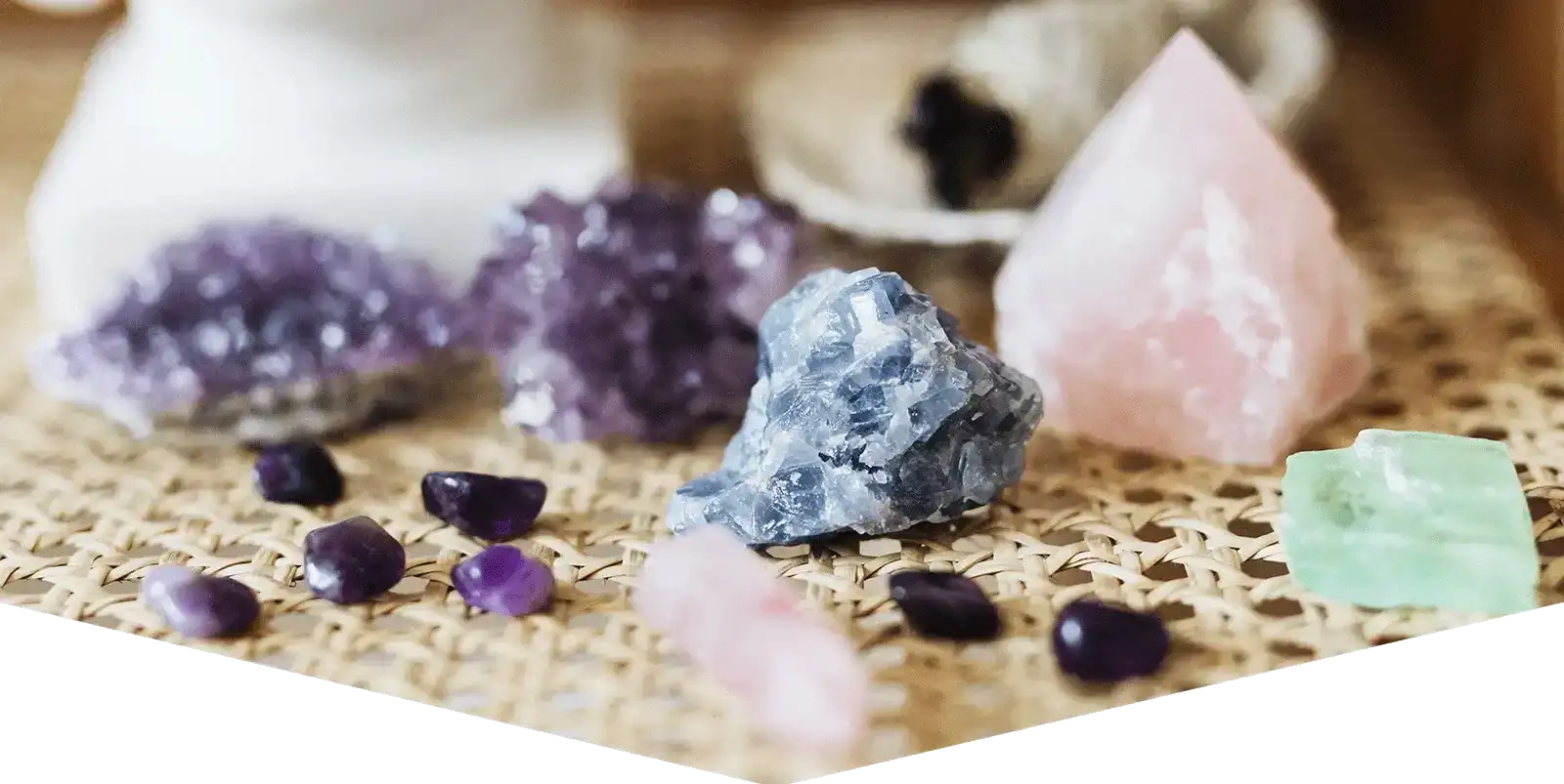 Une collection de pierres précieuses polies et brutes dans diverses teintes incluant le violet, le rose, le bleu, le vert et le noir disposées sur un tapis tissé.